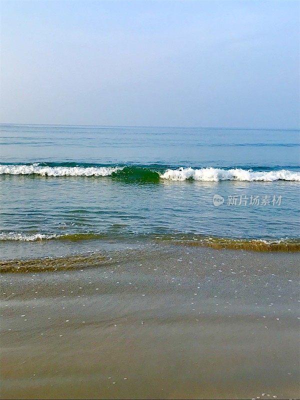 夏日的海滩，清澈平静的海浪拍打着海岸和金色的沙滩，蓝绿色的水反射着蓝天和涟漪，海滩度假，海浪泡沫/泡沫从潮汐和潮湿的沙子在阳光明媚的日子